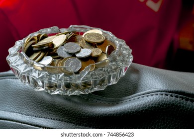 coins in a beautiful ashtray on dark red background - Shutterstock ID 744856423