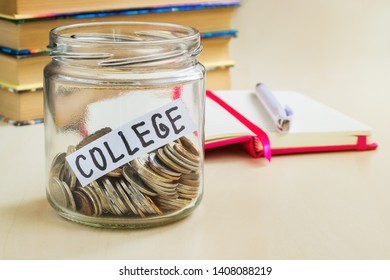 A Lot Of Coins And College Word In A Glass Jar Near A White Ballpoint Pen And Few Books On A Table. Saving Money For College And Education Concept. Planning For Future Expenses.