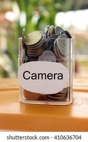 Coins in a glass container with a label camera. Financial concept.