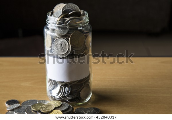 Coins in Glass jar with empty label.\
Concept image of personal finance, saving,\
investment.