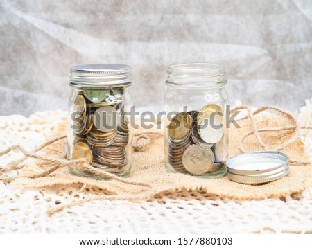 Coins in glass jar isolated on fabric    background with copy space. Saving money concept.