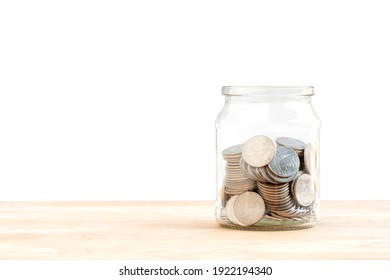 A lot of coins in a glass jar on wood table, how to keep money, saving money for your child, home, loan investment concept isolated on white background.