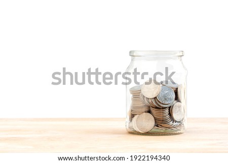 A lot of coins in a glass jar on wood table, how to keep money, saving money for your child, home, loan investment concept isolated on white background.
