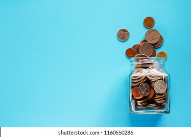 Coins in glass jar and outside, Thai currency money on blue background for business and finance concept