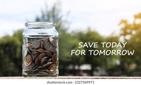 Coins in glass jar with the text save to day for tomorrow with blurred green trees background, concept of money savings                               - Shutterstock ID 2327369971