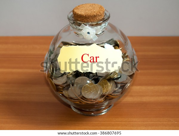 Coins in glass money jar with car label.
Financial concept.