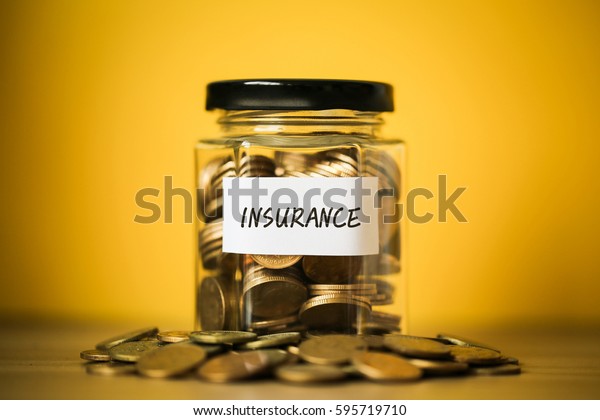 A lot coins in glass money jar with\
yellow background. Saving for Insurance\
concept.