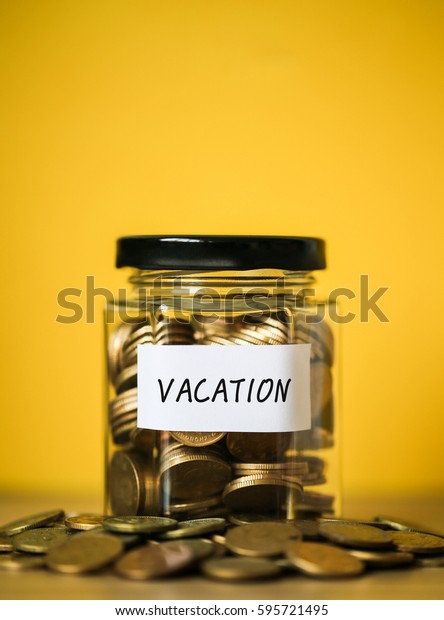 A lot coins in glass money jar with
yellow background. Saving for vacation
concept.
