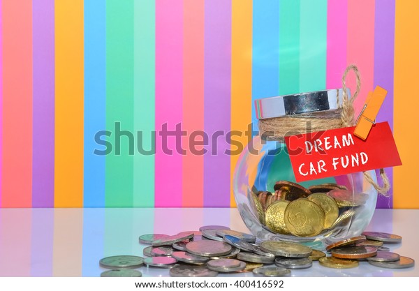 Coins in jar with Dream Car Fund label\
with multi color background - financial\
concept