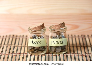 Coins In Jar. Writing Tax Pension On Two Jar With Wooden Pallet Background. Selective Focus With Shallow Depth Of Field.