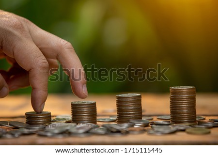  Coins a men's hand  placed and sorted coins on a wooden board.