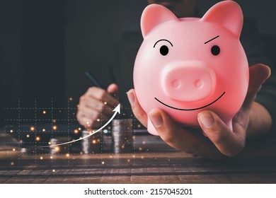 Coins with a money-saving concept and a profit graph of corporate finance in a piggy bank with money boxes for future tourist, house, and retirement funds on a blurred background. - Shutterstock ID 2157045201