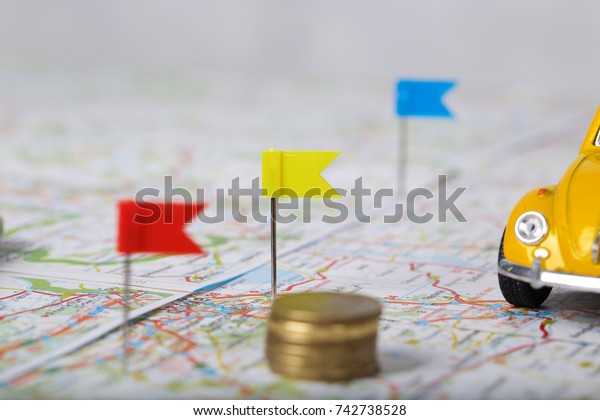 Coins on a\
map. Mini car in the background.\
Closeup