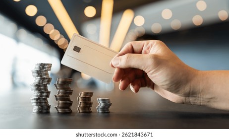 The coins on the table are shuffled back and forth between the left and right, while a businessman's hand holds a credit card.