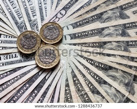coins of one sterling pound and background with american dollars bills 
