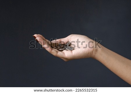 Coins in palm of woman hand isolated on dark gray background. 