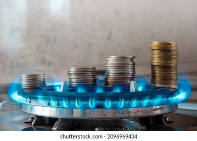 Coins pile up on a burning gas burner. The concept is to increase the cost of supply , payment for natural gas. - Shutterstock ID 2096969434