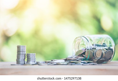 Coins placed  is on table. jar fall down Then there's the coin flowing out go coins, Indicates business growth. planning savings money of coins to buy a home concept property mortgage and investment. 