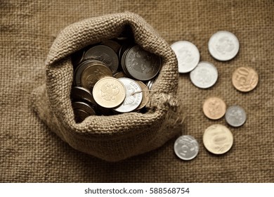 coins in a sack and some coins near on burlap background