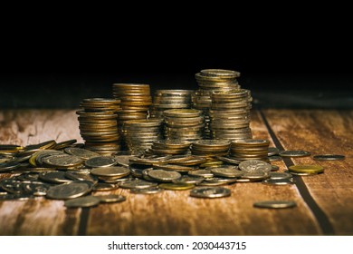 Coins are set up in rows of high and low gradients and coins scattered across the floor in a pattern that are stacked on an old wooden tabletop and black background.
