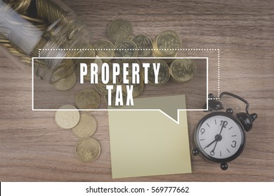 Coins spilling out of a glass jar on wooden background with PROPERTY TAX text . Financial Concept