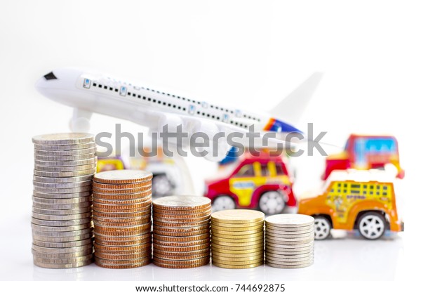 Coins stack with airplane and toy car on white\
background, concept of business growth, financial or money savings,\
with copy space for text.