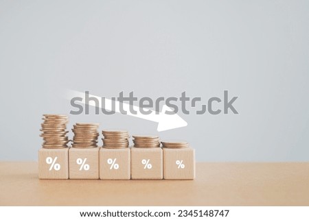 Coins stacking on wooden cube block with white down arrow and difference size percentage for  financial recession crisis, interest rate decline, investment reduce, risk management concept