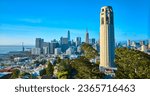 Coit Tower surrounded by trees with San Francisco downtown in background aerial