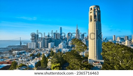 Coit Tower surrounded by trees with San Francisco downtown in background aerial