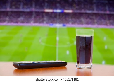 Coke Fizzy Drink, Tv Remote On A Table. Watching Football (soccer) Game And Having A Good Time.