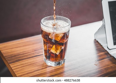 Coke Splashing From Glass On Wood Table Good Photo