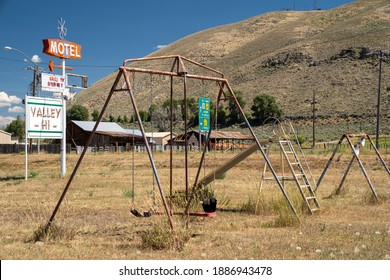 Cokeville, Wyoming - August 6, 2020: Swingset And Playground At An Old Abandoned Seedy Motel, With Overgrown Weeds In The Parking Lot