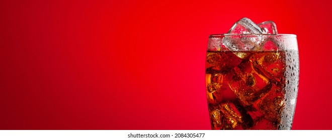 Cola beverage with ice. Fresh cold sweet drink with ice cubes. Over red background with copy space - Shutterstock ID 2084305477