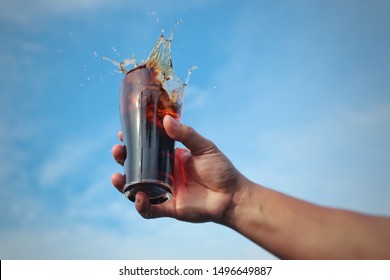 Cola  drink splashes out of glass and the sky background.
