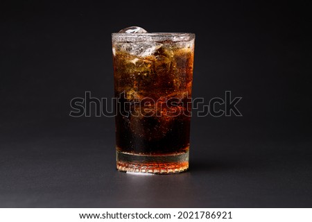 Cola in glass with clear ice cubes isolated on black background