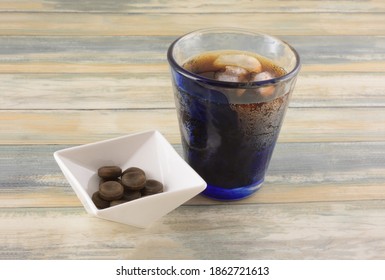 Cola Hard Candy In White Candy Dish With Cold Glass Of Cola With Ice Cubes