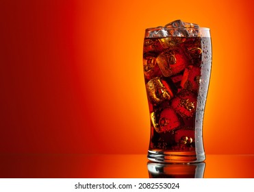 Cola with ice. Fresh cold sweet drink with ice cubes. Over red background with copy space