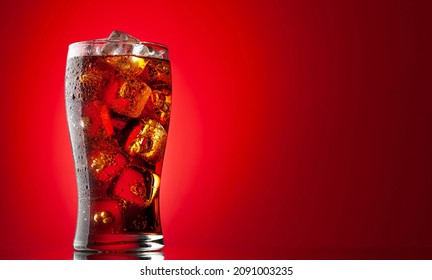 Cola with ice. Fresh cold sweet drink with ice cubes. Over red background with copy space - Shutterstock ID 2091003235