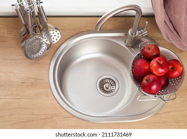 Colander With Apples On Silver Sink In Modern Kitchen