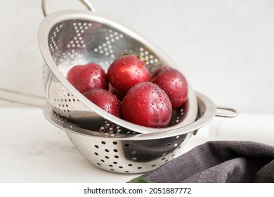 Colander with fresh ripe plums on table