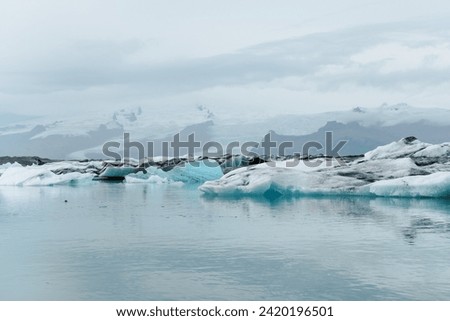 Cold arctic isolated Icelandic nature environment landscape of natural floating icebergs in blue glacial lake and snow covered mountains