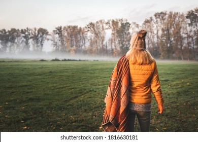 Cold Autumn Morning With Fog. Woman With Knit Hat And Blanket Standing In Nature While Camping Outdoors. Hiking At Fall Season