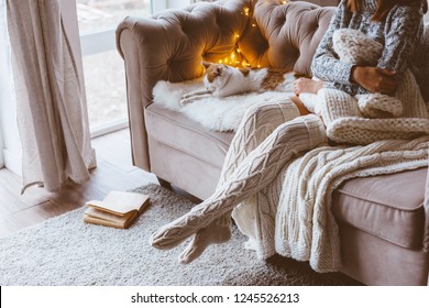 Cold Autumn Or Winter Weekend While Relaxing With Cat On A Couch. Lazy Day In Knitted Socks At Home. Cosy Scene, Hygge Concept.