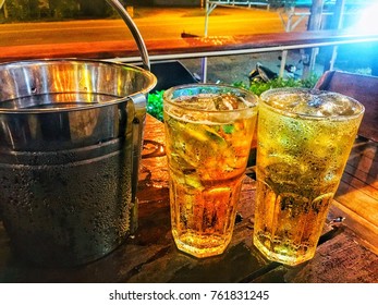 Cold beer in ice cubes with ice cubes next to it.