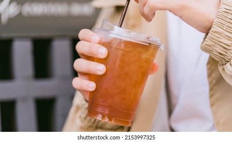 Cold Brew Iced Americano Coffee In A Bio Cup On Man Hand Drinking.herbal Ice Tea Drink.Ice Aroma Black Coffee, Espresso, Americano With Medium Roasted Coffee Beans.hipster Teen In Cafe With Cold Brew.