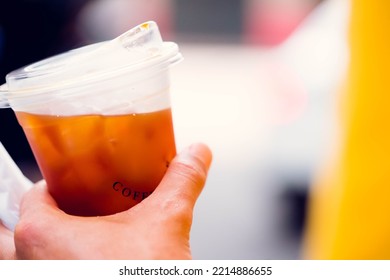 Cold Brew Iced Americano Coffee In A Bio Cup On Man Hand Drinking.herbal Ice Tea Drink.Ice Aroma Black Coffee, Espresso, Americano With Medium Roasted Coffee Beans.hipster Teen In Cafe With Cold Brew.