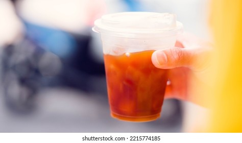 Cold Brew Iced Americano Coffee In A Bio Cup On Man Hand Drinking.herbal Ice Tea Drink.Ice Aroma Black Coffee, Espresso, Americano With Medium Roasted Coffee Beans.hipster Teen In Cafe With Cold Brew.