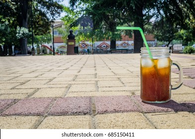 Cold brewed refreshing coffee with ice cubes served into mason jar outside in a strong summer sun