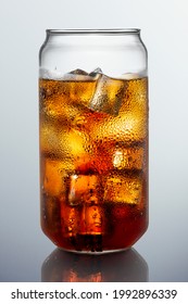 Cold carbonated drink over ice cubes in a can shaped glass