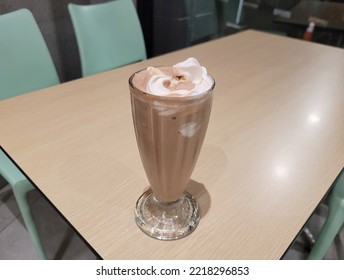 Cold Chocolate Milkshake Made With Vanilla Ice Cream Placed On Wooden Table At Fast Food Restaurant.